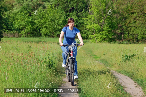 在騎自行車的綠色草地上快樂的年輕女子
