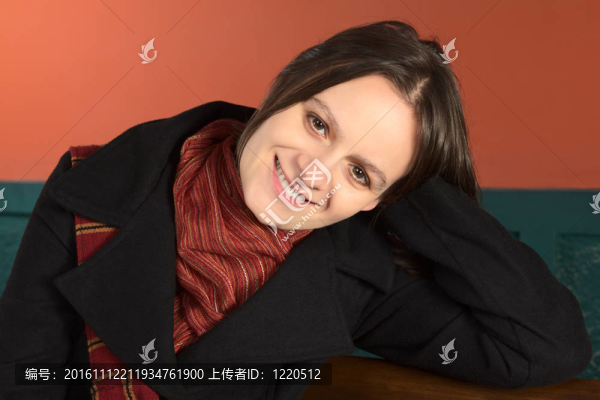 微笑的年輕白人婦女坐在長凳上，把頭靠在手臂上（選擇性聚焦，注視臉部）