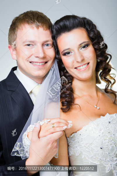 年輕優(yōu)雅的迷戀剛結(jié)婚的新娘和新郎抱著灰色背景的工作室肖像