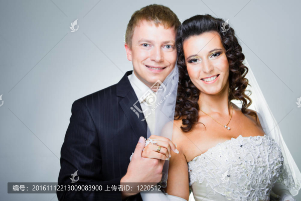 年輕優(yōu)雅的迷戀剛結(jié)婚的新娘和新郎抱著灰色背景的工作室肖像