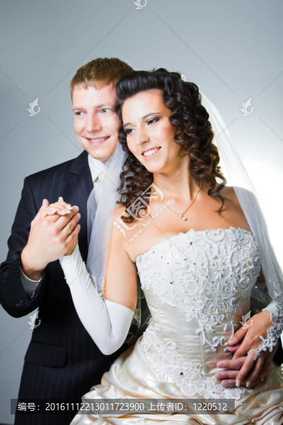 年輕優(yōu)雅的迷戀剛結(jié)婚的新娘和新郎抱著灰色背景的工作室肖像