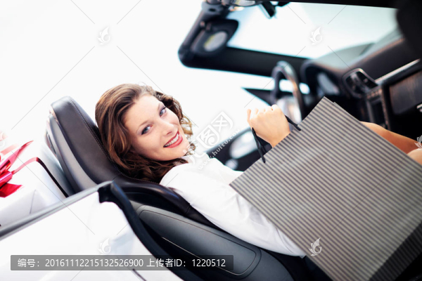迷人的女人在車與購物袋