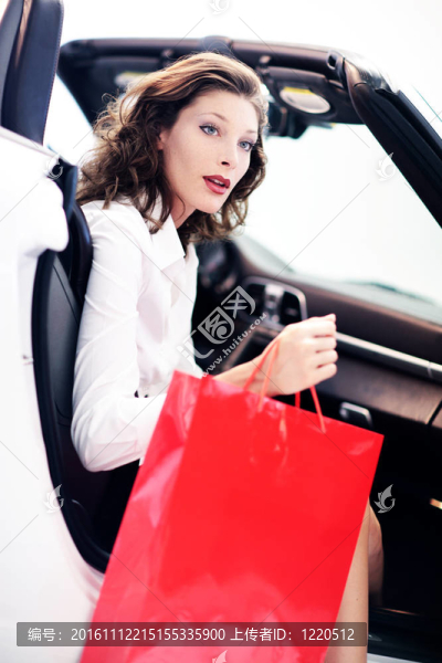 迷人的女人在車與購物袋