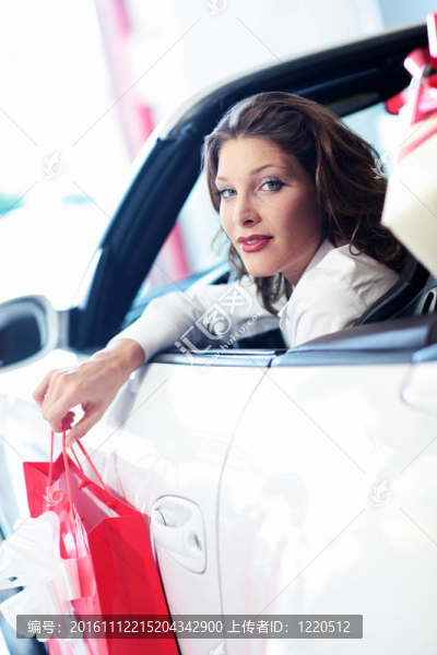 迷人的女人在車與購物袋