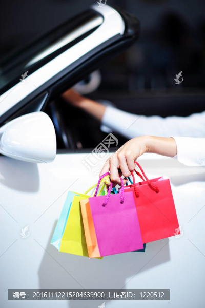 迷人的女人在車與購物袋