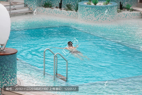 男子在游泳池的藍色水里游泳