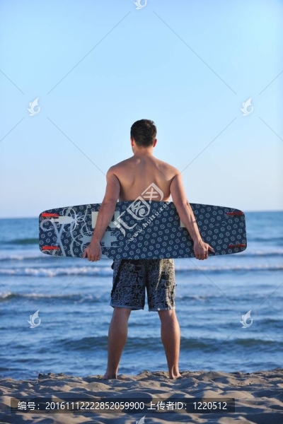 一個年輕人在海灘上的日落kitsurf肖像