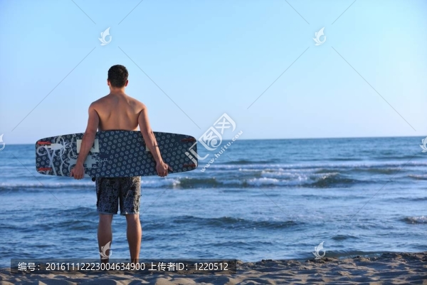 一個年輕人在海灘上的日落kitsurf肖像