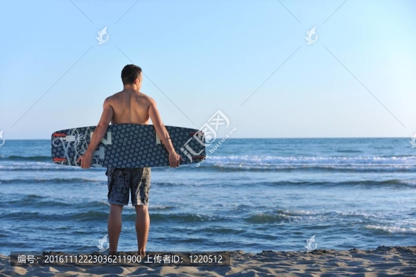 一個年輕人在海灘上的日落kitsurf肖像