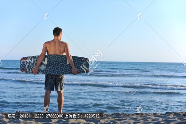 一個年輕人在海灘上的日落kitsurf肖像