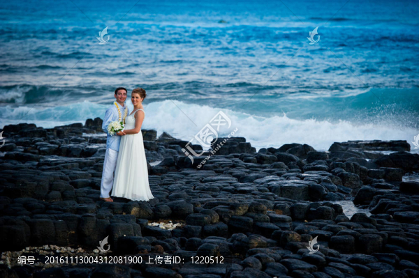 剛剛結婚。美麗的年輕夫婦在巖石海岸。