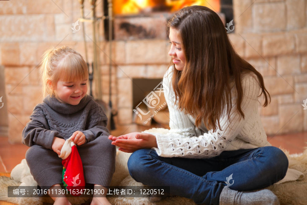 兩個(gè)女孩坐在爐邊，打開(kāi)圣誕禮物