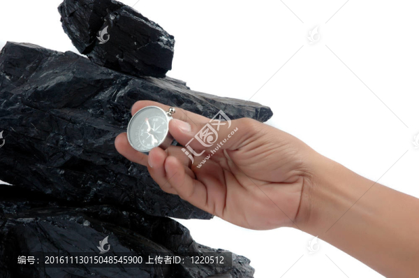 一堆堆的煤和一個由人舉行的指南針