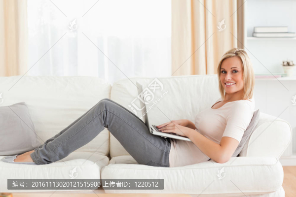 可愛(ài)的女人與筆記本電腦，而躺在沙發(fā)上