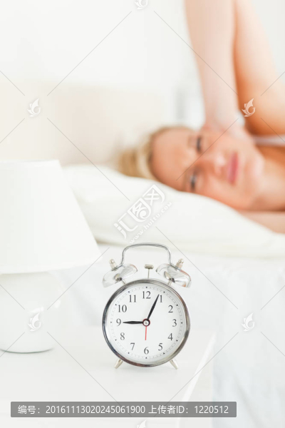 一個(gè)心煩意亂的女人叫醒她的鬧鐘的肖像