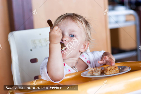 可愛的嬰兒吃蛋糕在椅子上