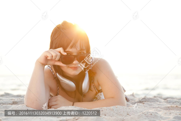 美麗的黑發(fā)女孩在沙灘的耳機(jī)。