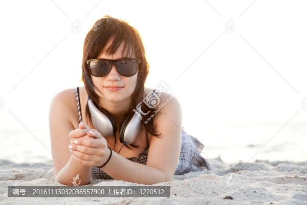 美麗的黑發(fā)女孩在沙灘的耳機(jī)。