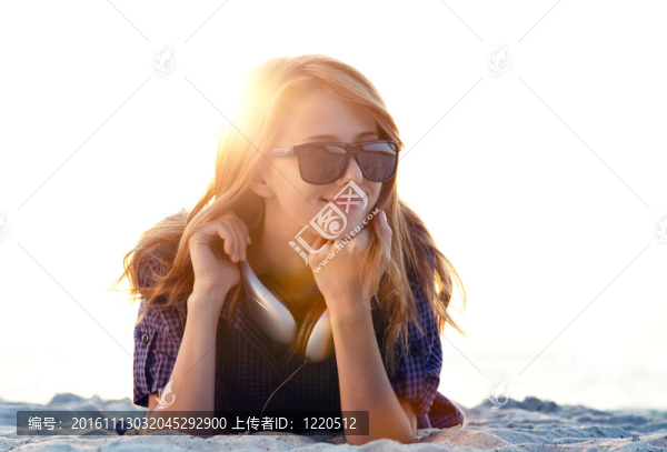 美麗的紅發(fā)女孩在沙灘的耳機(jī)。