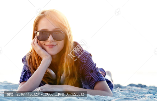 美麗的紅發(fā)女孩在沙灘的耳機(jī)。