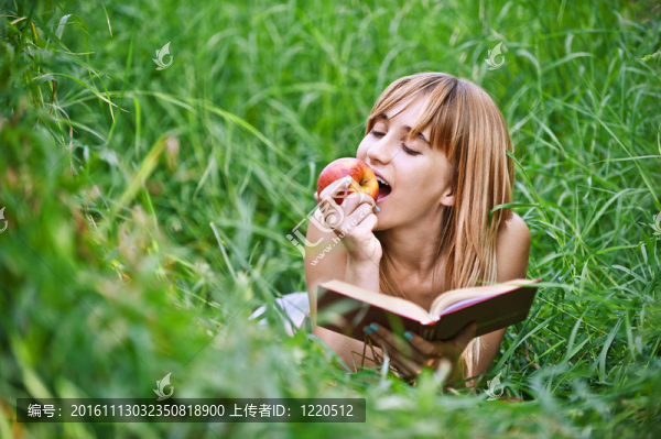 年輕婦女吃蘋果和讀書