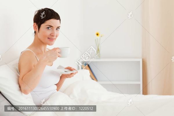 可愛的女人一邊喝茶一邊看著相機