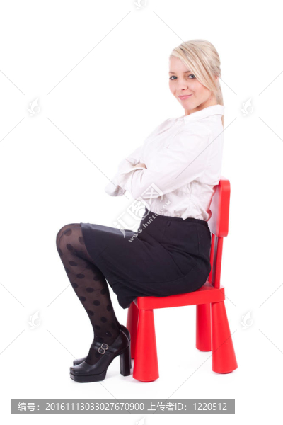 坐在紅色的；孩子的椅子年輕女子