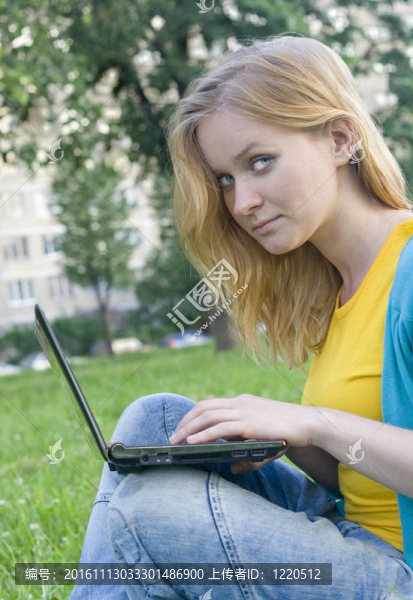 漂亮的女人在綠色草地上有筆記本電腦