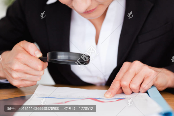 女性手拿放大鏡在圖表上方