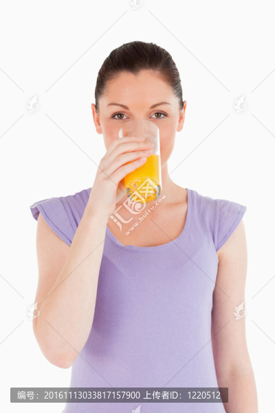 漂亮女人站著喝一杯橙汁