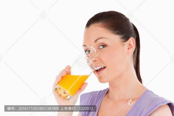 有吸引力的女人喝一杯橙汁，而站在白色背景