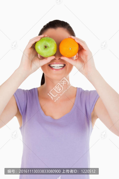 站在白色背景上的一個迷人的女人在玩水果的肖像