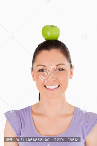 一個漂亮的女人在一個白色背景上站在她頭上拿著一個蘋果的肖像