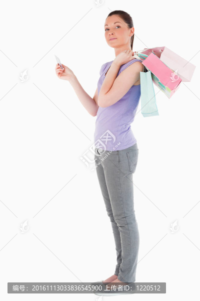 漂亮的女人與信用卡持有購(gòu)物袋，而站在白色背景
