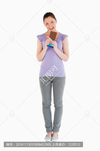 可愛的女人站著吃巧克力塊