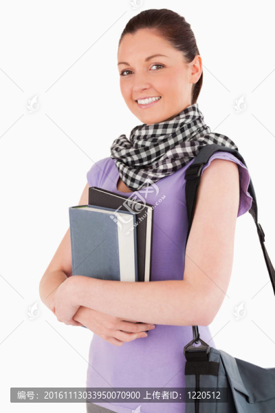 迷人的學(xué)生拿著書和她的書包站著