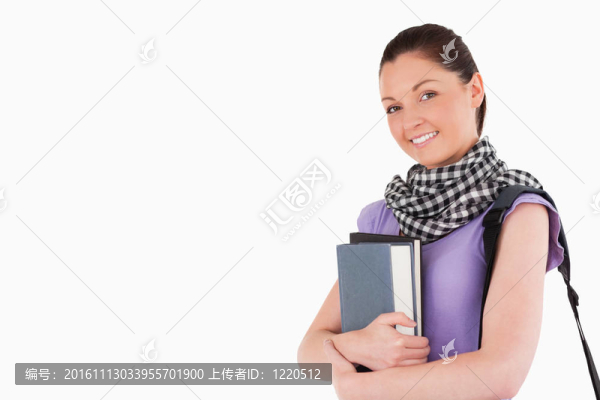 漂亮的學(xué)生拿著書和她的書包站著