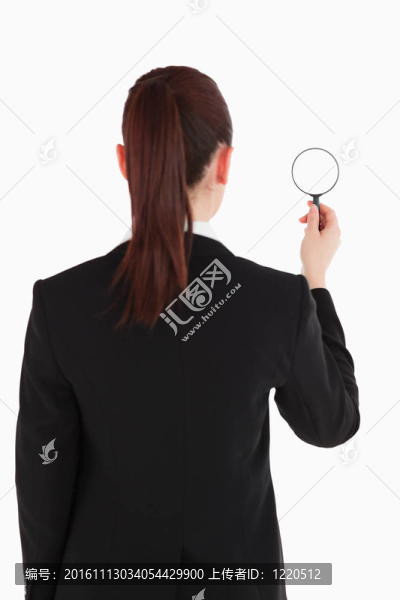 在訴訟中被回相機(jī)，拿著magnifyng玻璃在白色背景下站著美麗的女人