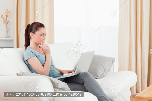 美女坐在客廳的沙發(fā)上放松自己的筆記本電腦