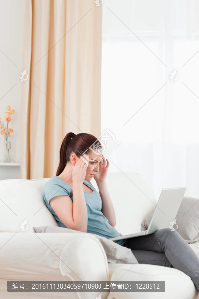 美麗的心煩意亂的女人與她的電腦賭博，而坐在客廳的沙發(fā)上