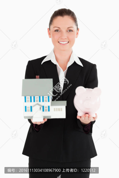 漂亮的女人拿著一個存錢罐和一個微型房子