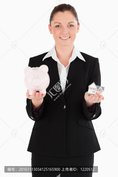 穿著白色的背景，抱著小豬存錢罐和迷你房子的漂亮女人