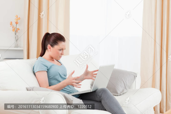 迷人的心煩意亂的女人與她的電腦賭博，而坐在客廳的沙發(fā)上