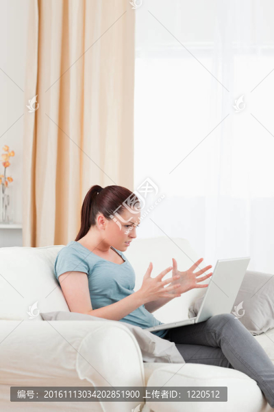 好看的女人在客廳里坐在沙發(fā)上玩電腦時心煩意亂