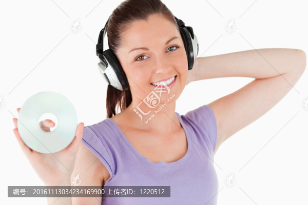 迷人的女人手持耳機站在CD