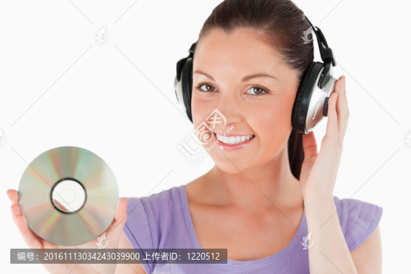 迷人的女人手持耳機站著CD
