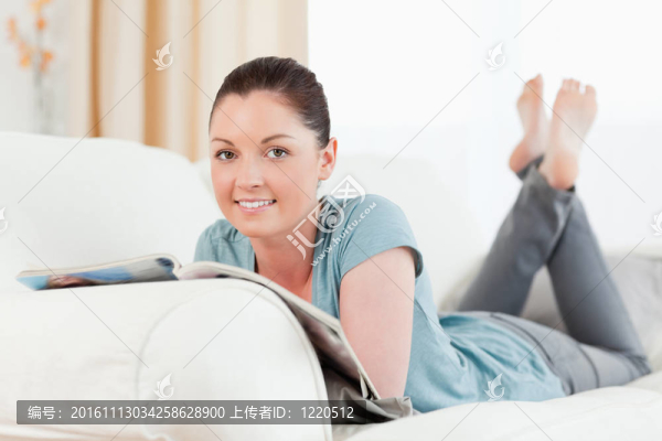 漂亮的女人躺在沙發(fā)上看雜志