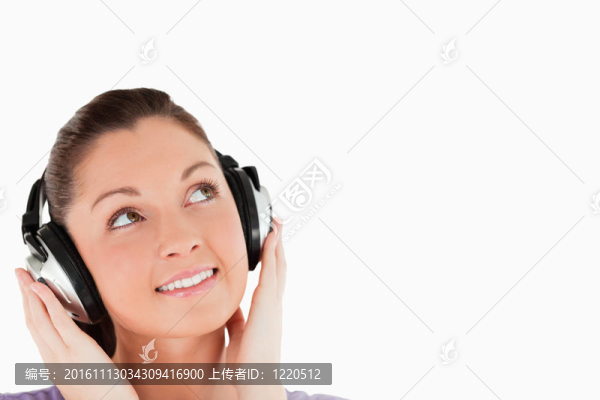 一個(gè)可愛的女人擺著耳機(jī)，站在白色背景的肖像