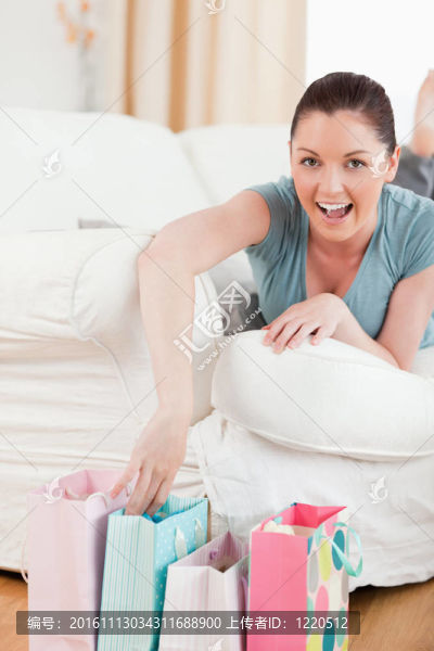 迷人的女人在客廳的沙發(fā)上摸她的購(gòu)物袋