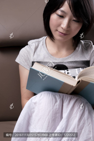 年輕女子坐在沙發(fā)上看書